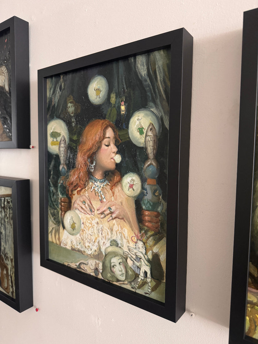 Framed artwork of a woman with red hair and decorative elements on a wall.