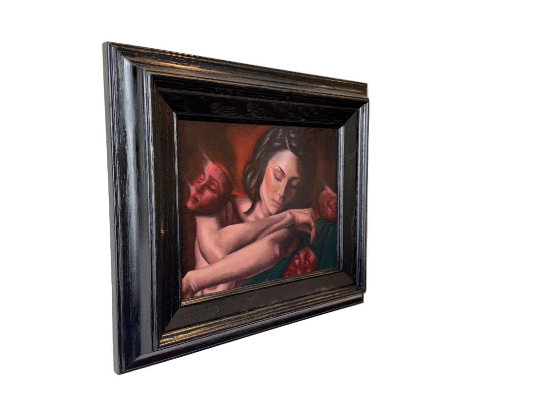 Framed artwork of a woman holding a child with red roses on a wall.