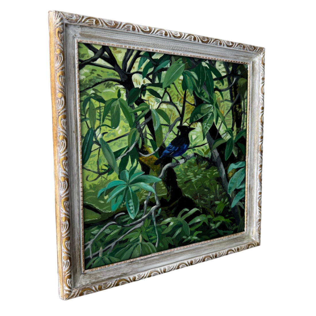 Framed painting of a bird in a jungle setting on a white wall