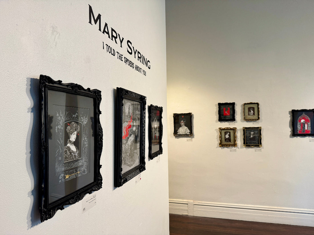 Art gallery with framed artworks on white walls, featuring text and artistic designs.