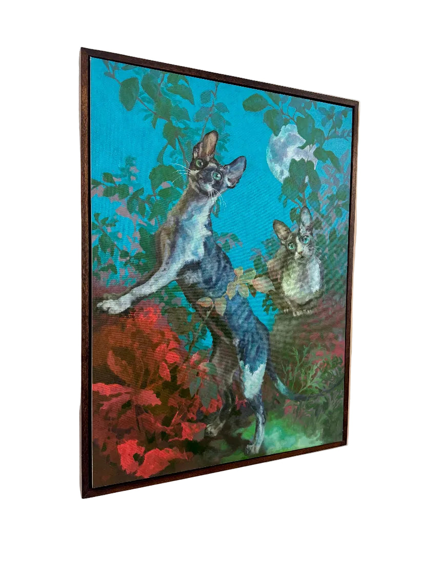 Framed artwork of two cats in a garden setting on a beige wall.