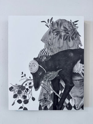 A black and white surreal artwork depicting a dark goat-like figure with a mask, draped fabric, and leafy branches, shown hanging on a light gray wall.