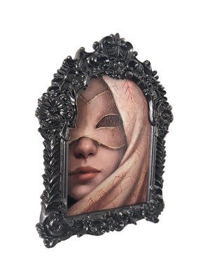 Framed artwork of a person wearing a mask with intricate details on a beige wall.