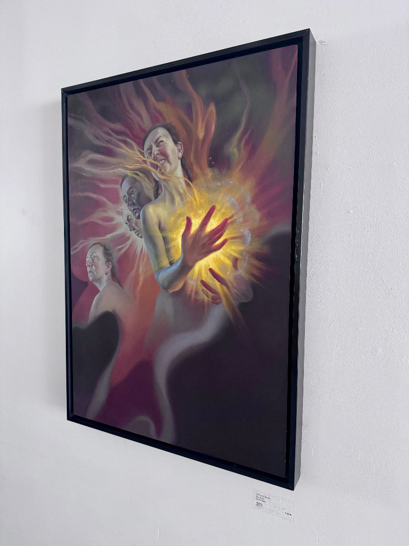 A framed surreal art print hanging on a white gallery wall. The artwork depicts two stylized human figures with glowing yellow, orange, and red energy effects against a dark purple and black background.