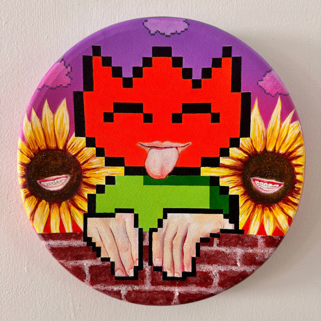 Pixelated design with a cat face, sunflowers, and a brick background on a circular object.