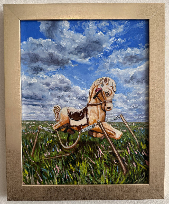 Framed artwork of a riding horse with a blue sky and greenery background