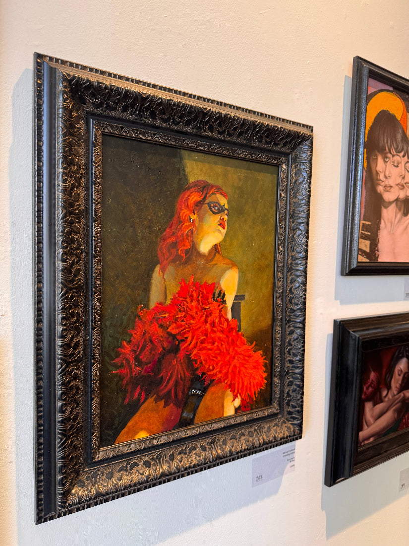 Framed painting of a woman with red hair and flowers on a wall with other artworks.