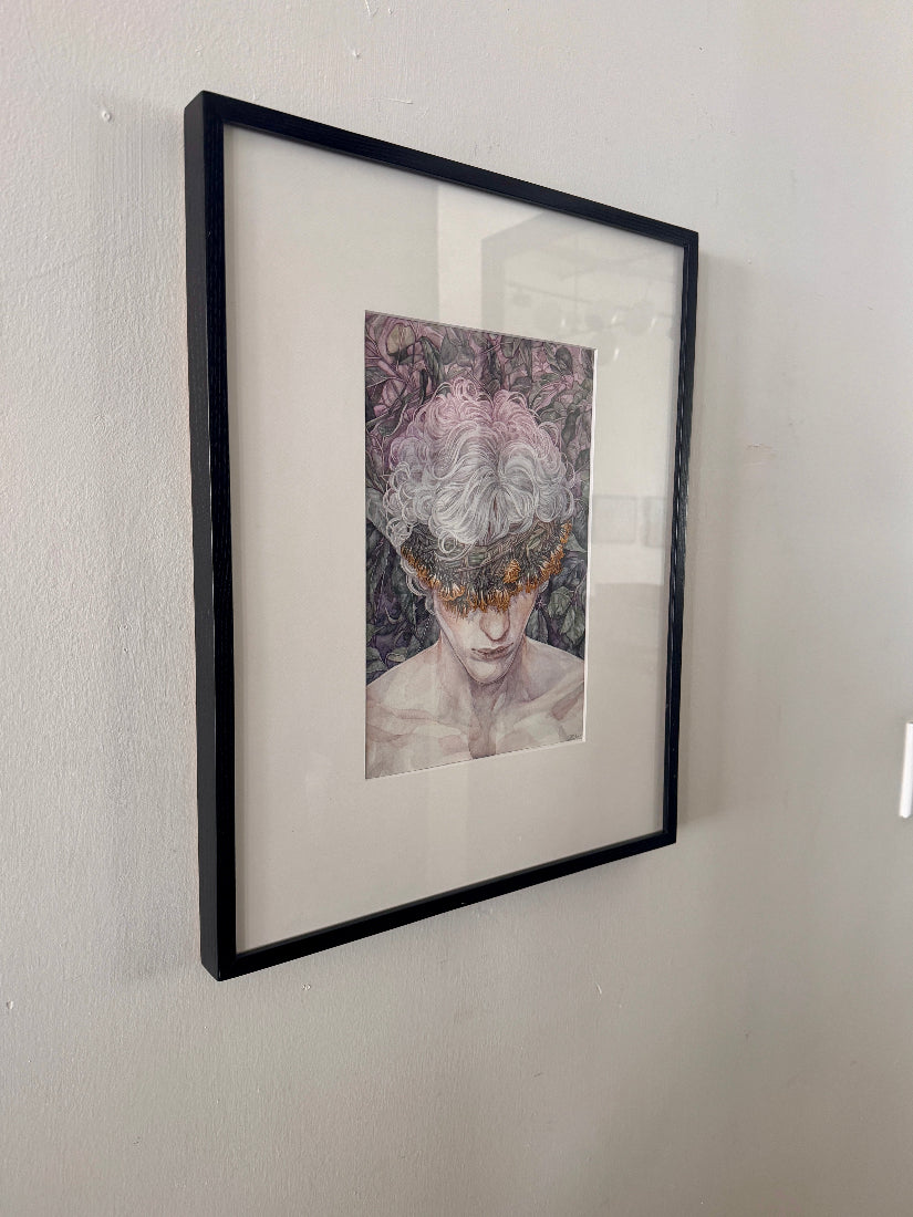Framed artwork of a person with floral headpiece on a white wall