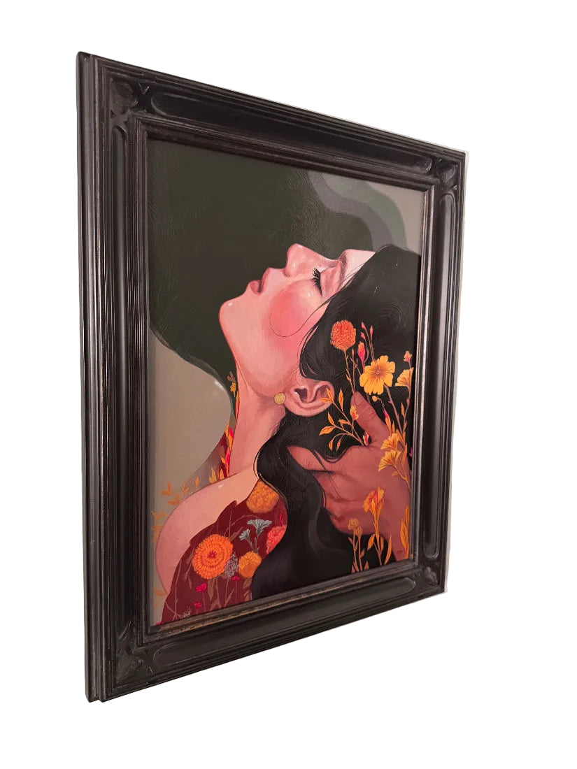 A framed painting featuring a stylized portrait of a woman with dark hair and orange flowers, displayed on a white wall.