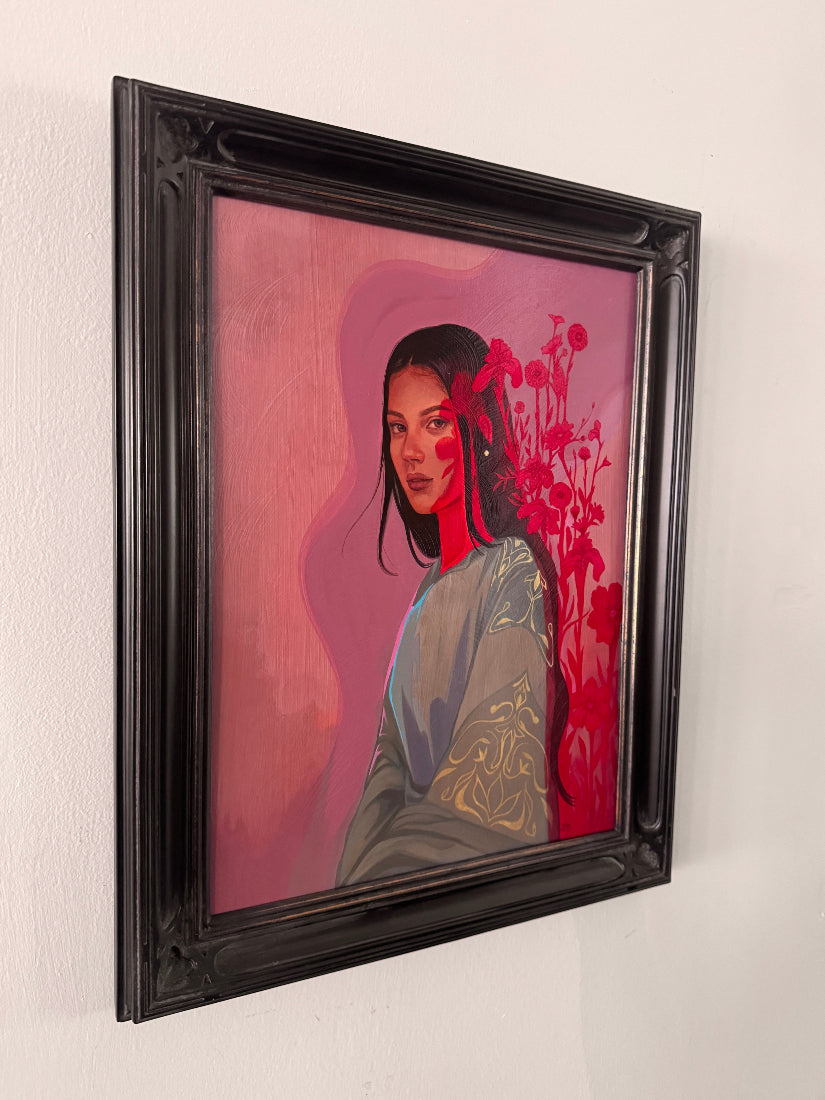 A framed portrait painting of a woman with dark hair, set against a pink and red background, housed in a thick black ornate frame and hanging on a white wall.
