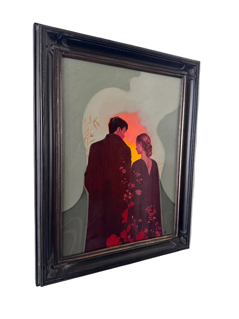 A framed painting depicting a couple in dark clothing standing before a glowing orange and red circular light on a muted gray-green background, hung on a white wall.