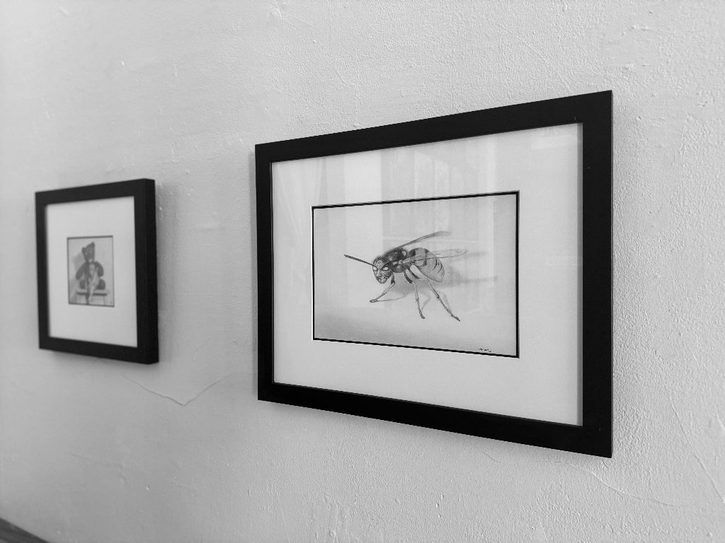 Two framed black and white artworks on a wall.