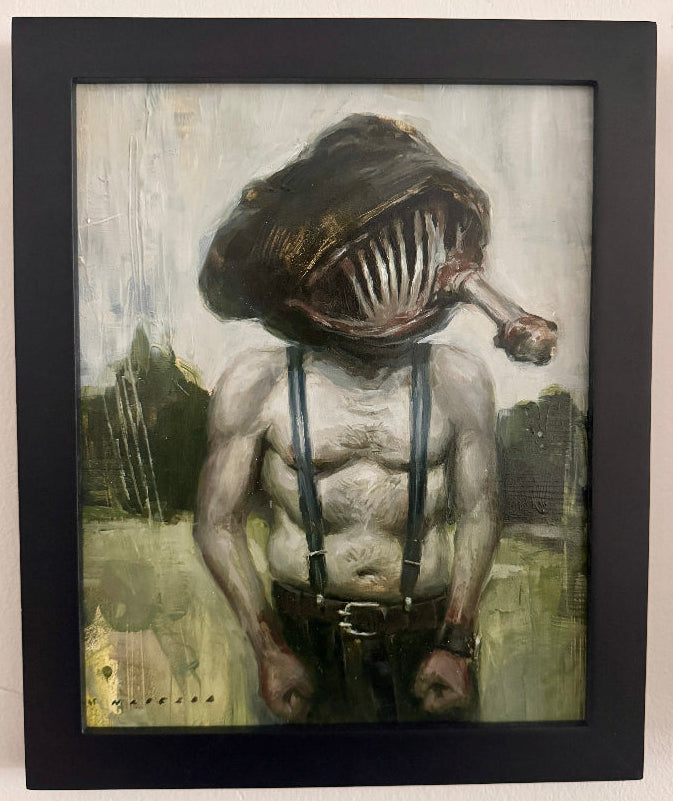 Framed artwork of a creature with a fish head on a beige wall