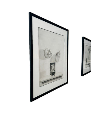Two framed black and white drawings on a white wall.