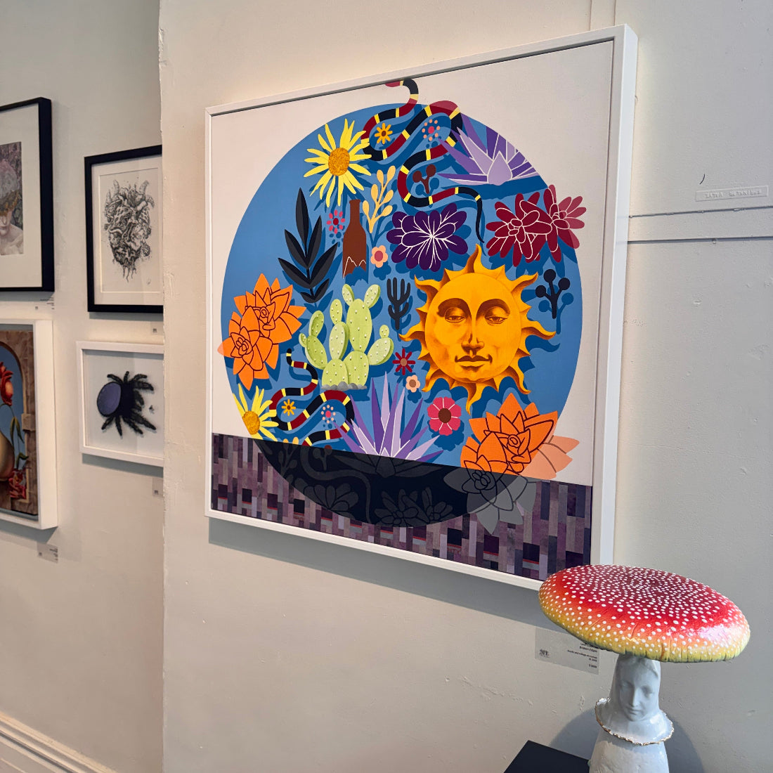 Colorful abstract artwork with a sun and flowers on a wall, with a small mushroom-shaped stool in front.