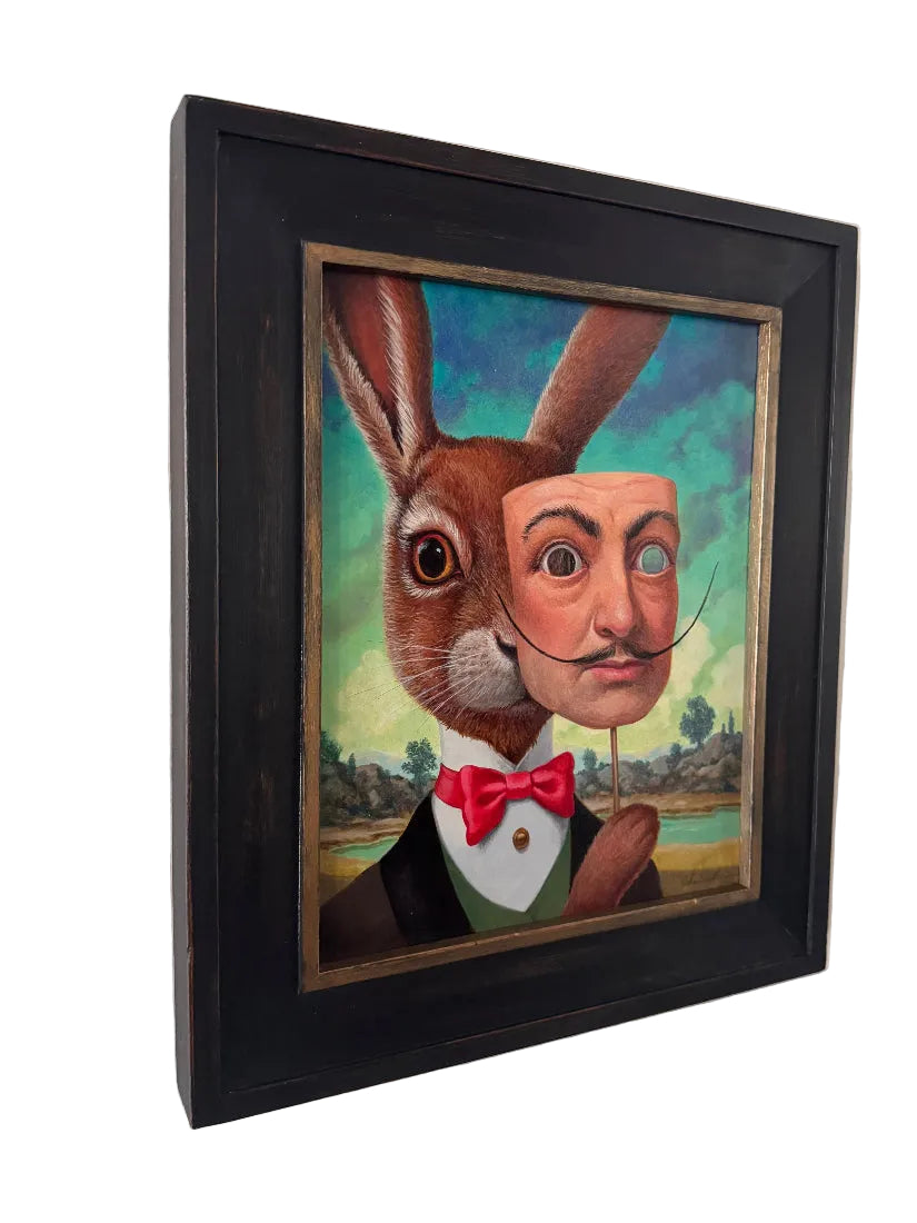 Framed artwork of a rabbit with a human face and bow tie on a white wall.