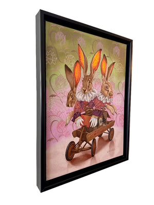 Framed artwork of two rabbits in a wheelbarrow on a decorative wall.