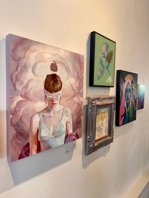Art gallery wall with various artworks including a prominent painting of a woman with a blindfold.