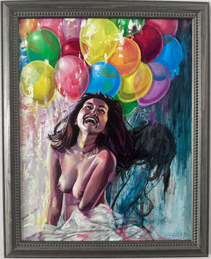 A framed painting on a white wall, depicting a laughing nude woman with dark hair surrounded by colorful balloons in yellow, green, red, blue, pink, and purple. The artwork is housed in a dark gray textured frame.