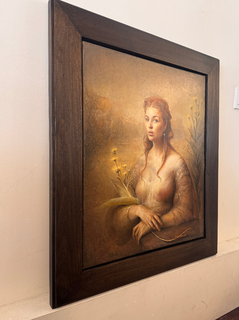 Framed portrait of a woman with a natural setting on a beige wall.