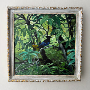 Framed painting of birds in a jungle setting on a white wall