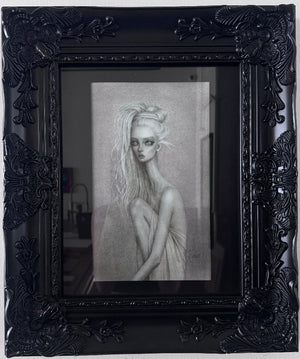 A framed black and white portrait drawing of a woman with long hair, set within an ornate black frame against a light wall.