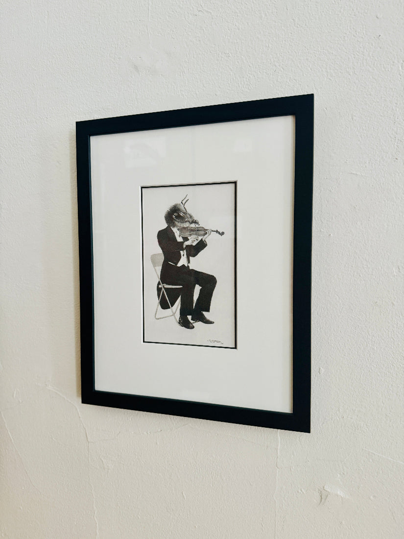 Framed black and white artwork of a bee playing a violin on a white wall.