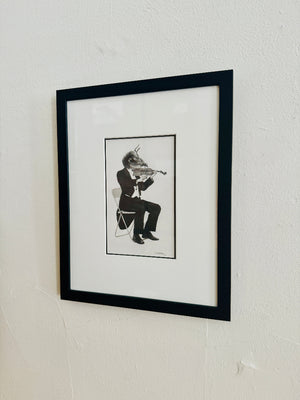 Framed black and white artwork of a bee playing a violin on a white wall.