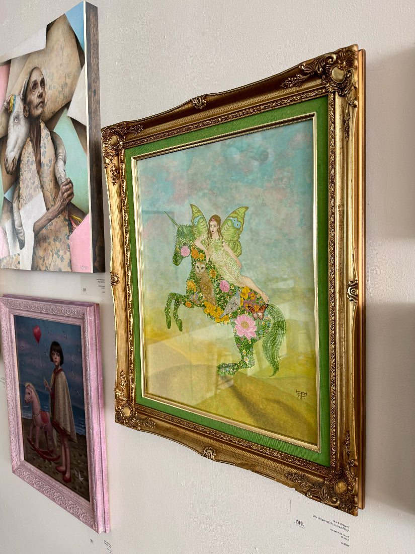 Decorative artwork with a fairy on a horse in a gold frame, surrounded by other framed pictures.