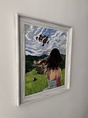 Framed artwork with a landscape scene and people, on a plain background