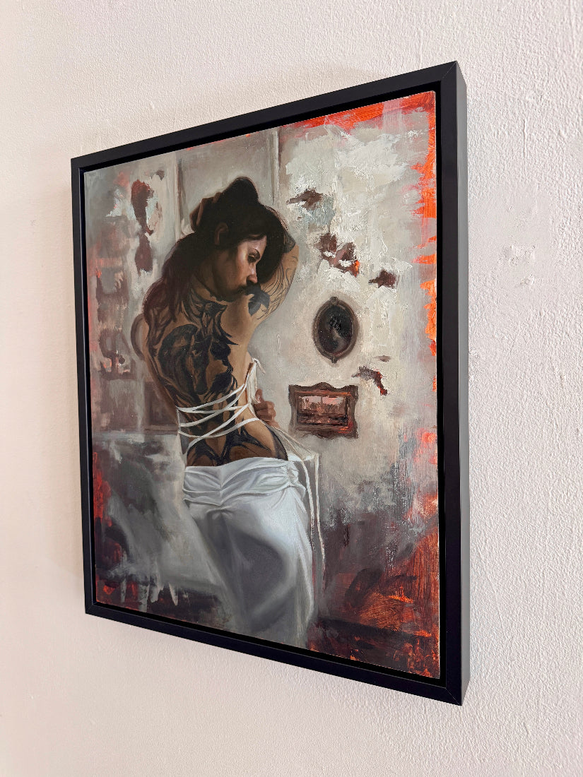 Framed artwork of a woman with tattoos sitting in a room with decorative elements.