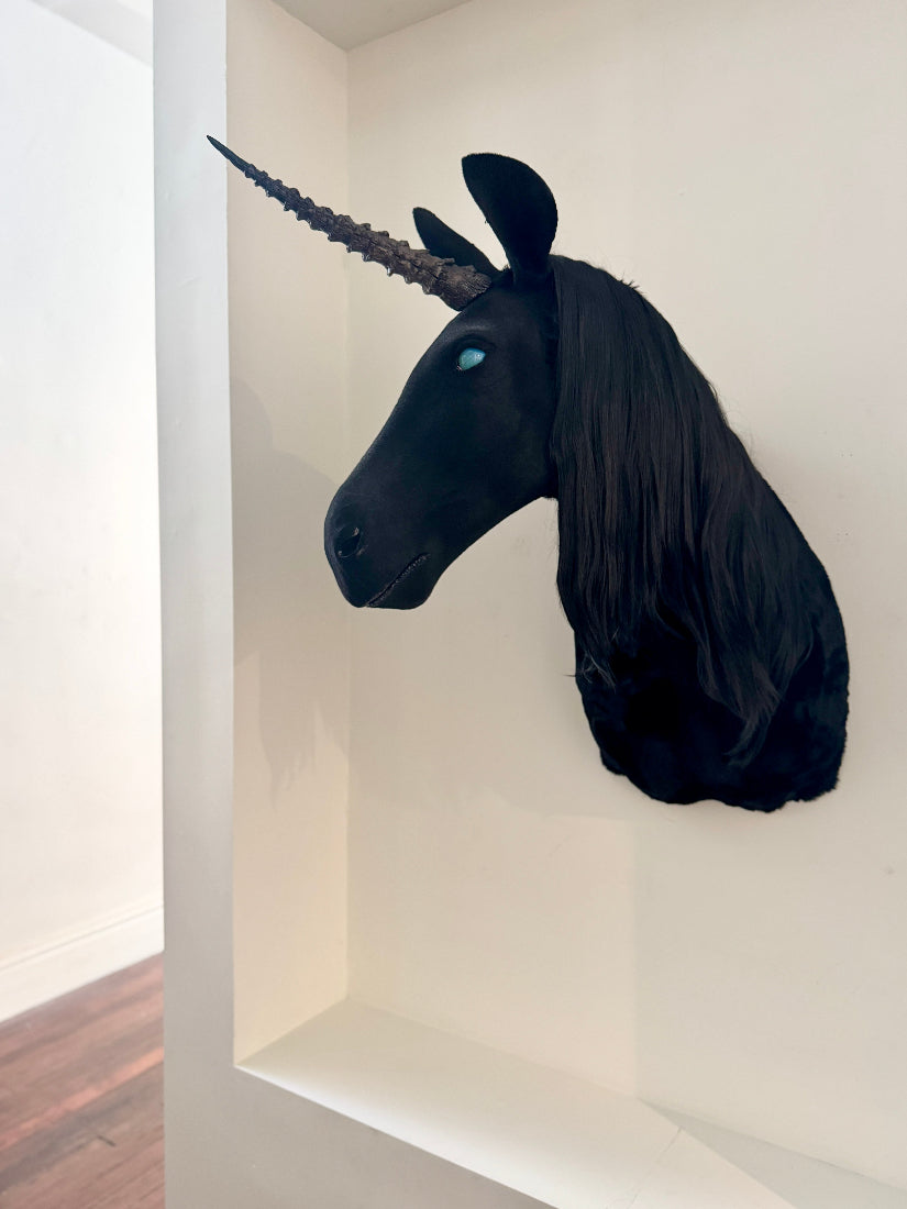Black unicorn head sculpture on a white wall
