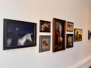 Art gallery wall with framed paintings of various subjects