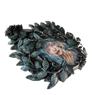 Decorative brooch with leaf design and portrait on a white background