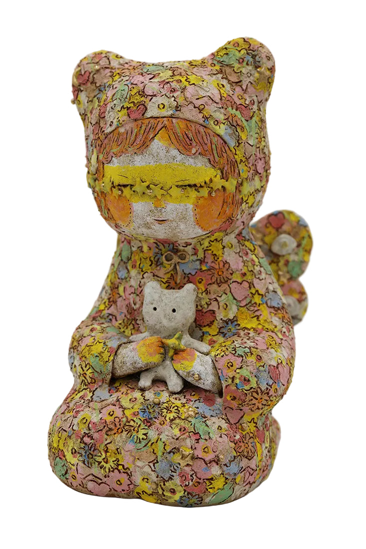 A handmade ceramic figurine of a bear-like character wearing a floral-patterned hat and holding a small white cat, photographed against a neutral light gray background.
