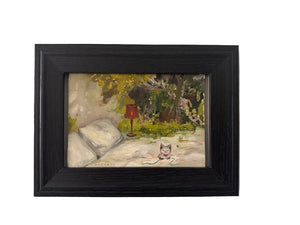 Framed painting of a landscape with a cat on a white wall