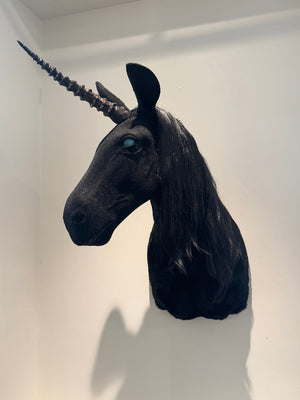 Black unicorn head sculpture on a white wall