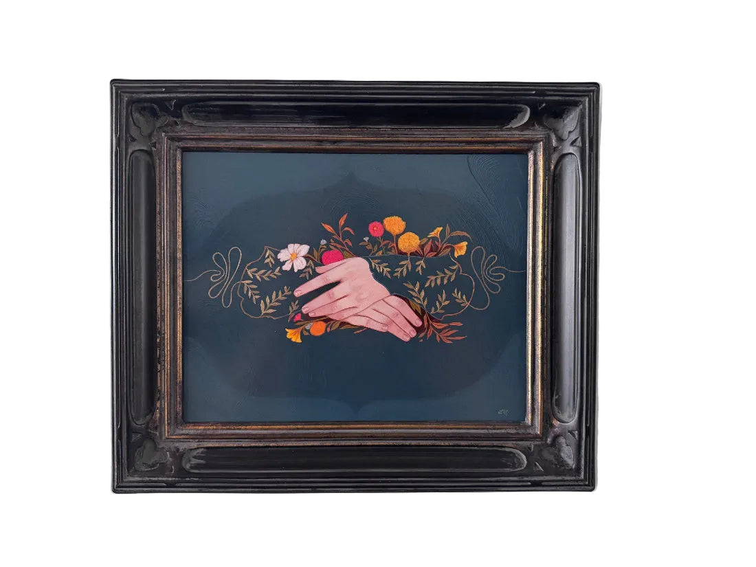 A framed painting featuring a hand painted over a floral arrangement on a dark teal background, housed in an ornate black wooden frame and mounted on a light gray wall.