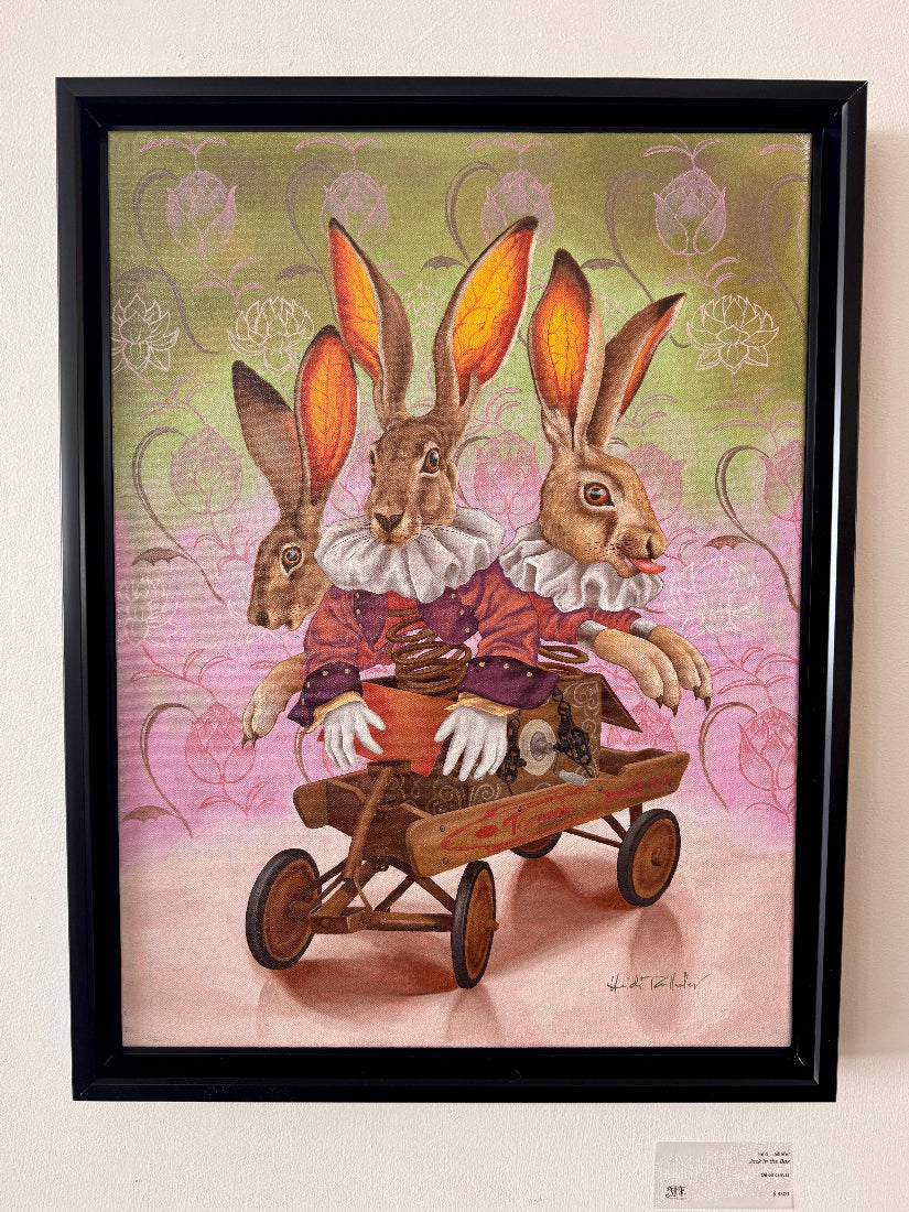 Framed artwork of three rabbits in a decorative setting with a pink and green background.