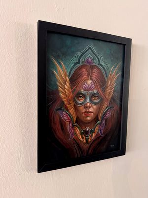 Framed artwork of a person with wings and a mask on a beige wall