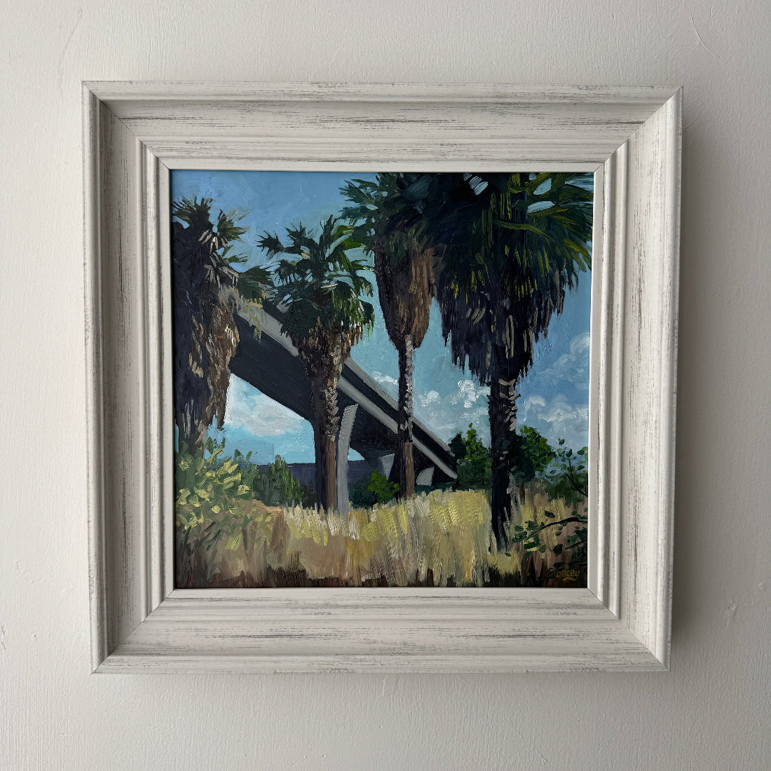 Painting of palm trees under a bridge with a blue sky.