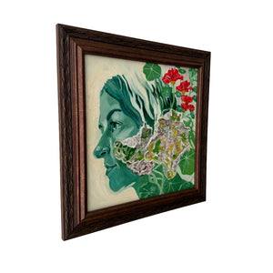 Framed artwork of a woman's profile with floral elements on a white wall