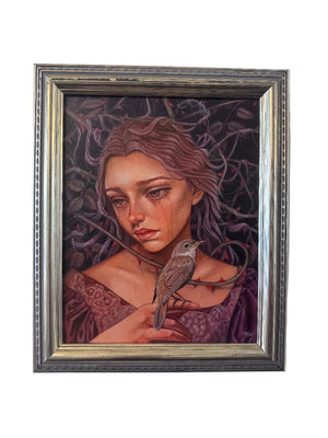A framed portrait painting of a woman with a small bird perched on her shoulder, displayed against a plain light gray wall. The artwork features a dark, moody background with purple and black tones, and the woman has reddish-brown hair and a purple garment.