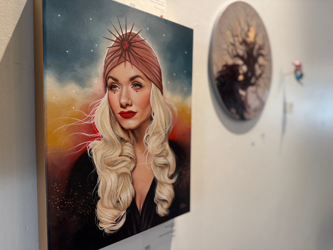 Artistic portrait of a woman with a turban on a wall next to another artwork.