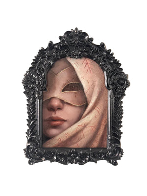 Framed artwork of a person wearing a mask with decorative elements on a beige wall.