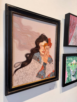 Framed artwork of a woman with long hair and floral patterns on a wall.