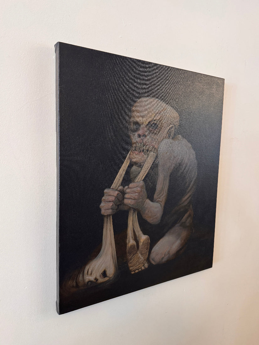 A vertical canvas painting hanging on a light beige wall, depicting a skeletal figure kneeling and holding a large bone structure in its hands against a dark background.