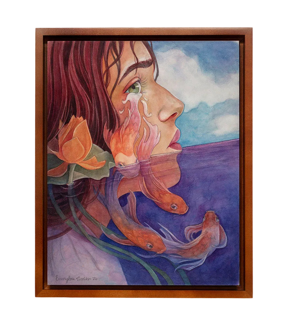 A framed painting on a light wall, depicting a woman's profile with flowing red hair, an orange flower, and orange fish over a blue-purple landscape. The artwork is enclosed in a warm brown wooden frame.