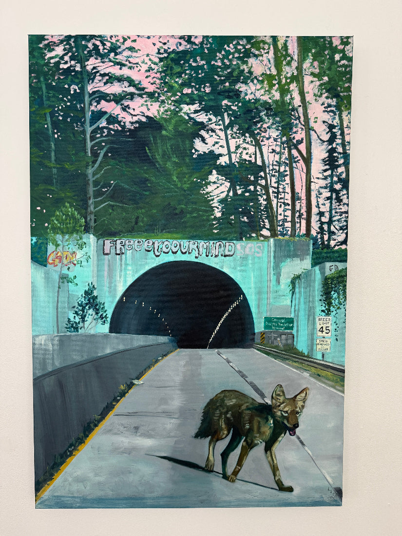 Coyote standing on a road leading to a tunnel with 'Free Your Mind' sign