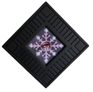 Painting with a pink snowflake design and eye in a black frame on a white background